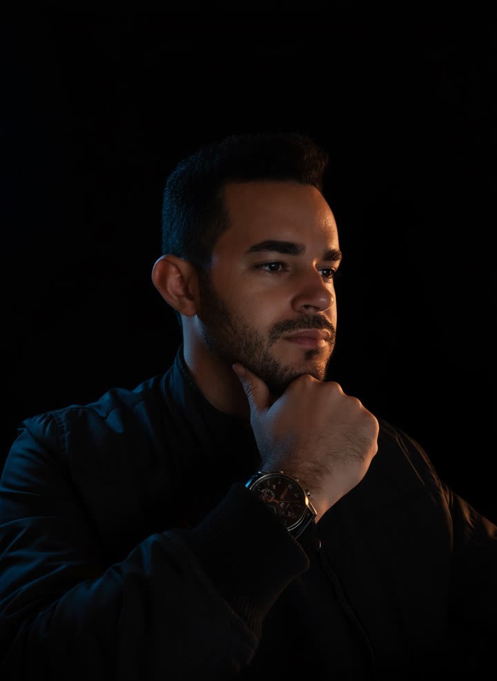 Retrato de Josimar, pensativo, com a mão no queixo e luz laranja no rosto